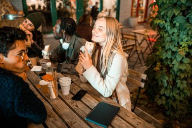 Bayan, arkadaşlarıyla bir şeyler atıştırıyor.