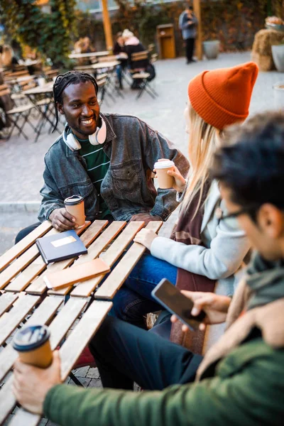 Šťastný Afroameričan chlap při pohledu na ženu v pouliční kavárně — Stock fotografie