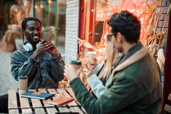 Feliz hombre afroamericano sosteniendo el teléfono móvil en la cafetería —  Fotos de Stock