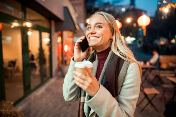 Feliz señora bonita usando teléfono inteligente mientras camina al aire libre — Foto de Stock