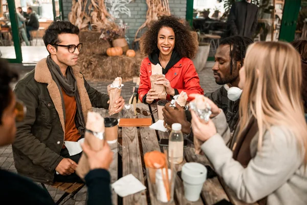 Happy young friends sitting in street cafe with snacks — 스톡 사진