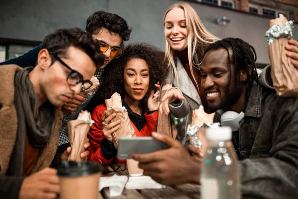 Mladí šťastní přátelé těší video v pouliční kavárně — Stock fotografie