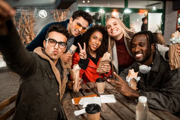 Heureux jeunes hommes et femmes posant à la caméra dans le café de la rue — Photo