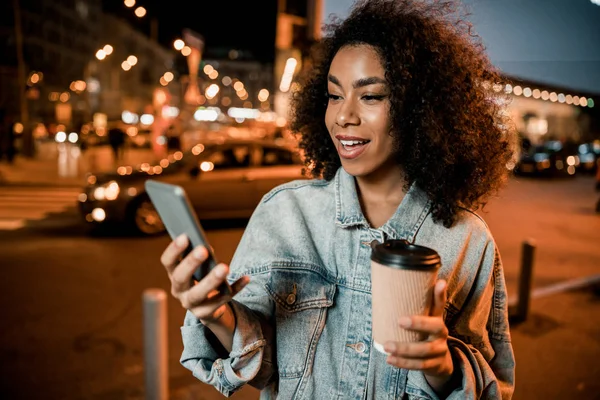 Mutlu Afro-Amerikan kadın şehirdeki telefon ekranına bakıyor. — Stok fotoğraf