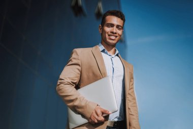 Sokağın ortasında dizüstü bilgisayarı olan mutlu bir genç adam.