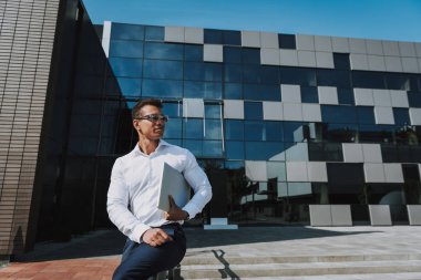 İş merkezinin yanında bilgisayarı olan neşeli bir yönetici.