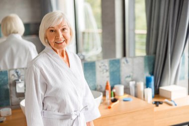 Neşeli yaşlı kadın spa salonunda vakit geçiriyor.