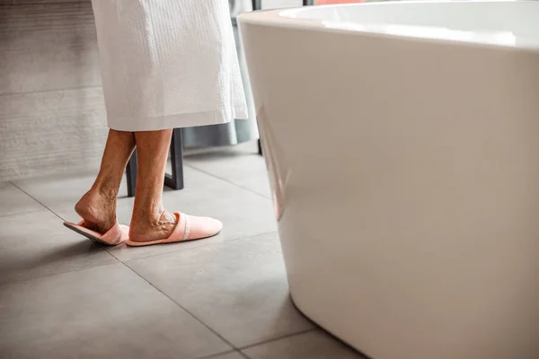 Oude dame in pantoffels in de badkamer — Stockfoto