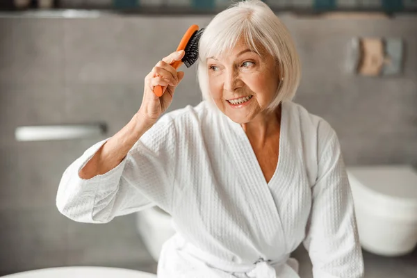 素敵な老婦人ブラッシング髪と笑顔 — ストック写真