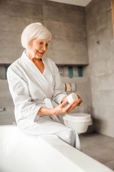 Alegre anciana sosteniendo tarro de crema — Foto de Stock