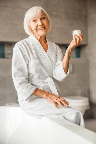 Fröhliche ältere Frau mit einem Glas Sahne — Stockfoto