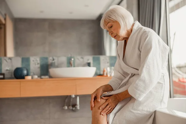 Upset old lady feeling pain in her knee — Stock Photo, Image