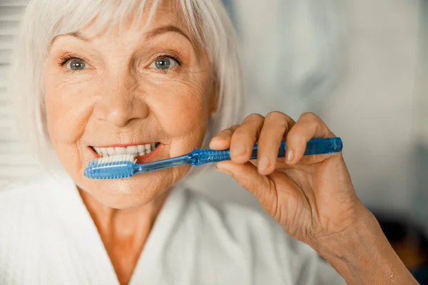 Sabahları dişlerini fırçalayan güzel yaşlı kadın. — Stok fotoğraf