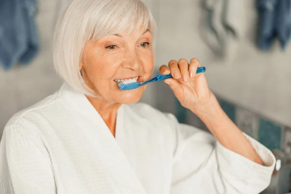 Старшая леди чистит зубы утром — стоковое фото