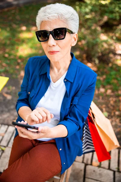 Encantadora señora mayor usando el teléfono celular en la calle — Foto de Stock