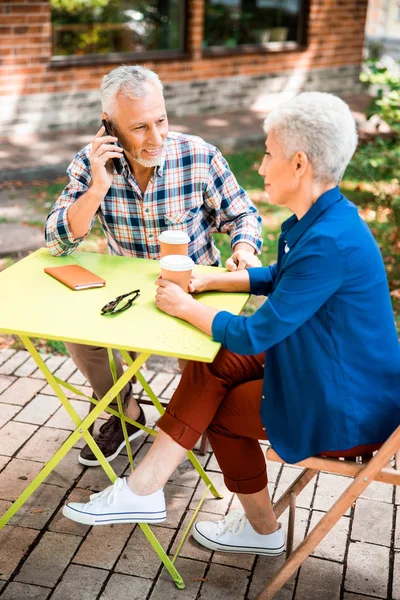 Старший мужчина разговаривает по телефону во время встречи с леди — стоковое фото
