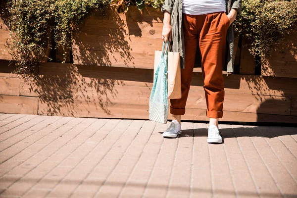 Femme âgée tenant sac en papier shopping et sac filet — Photo