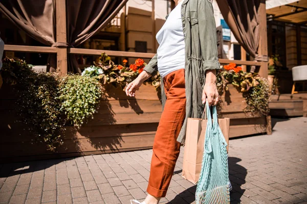 Femme âgée portant sac en papier shopping et sac filet — Photo