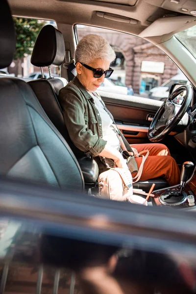 Anciana en gafas de sol sentada en coche — Foto de Stock