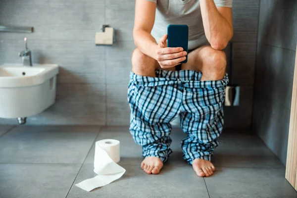 Anak muda menggunakan smartphone modern di toilet — Stok Foto