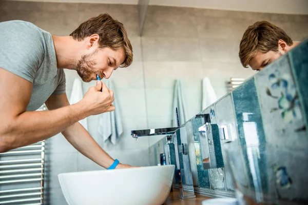 Knappe bebaarde heer poetsen tanden in de badkamer — Stockfoto