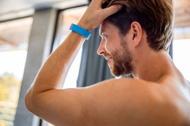 Yakışıklı genç adam saçlarına dokunuyor ve gülümsüyor.