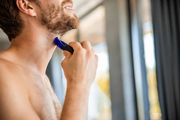 Smiling young man removing stubble from neck — 스톡 사진