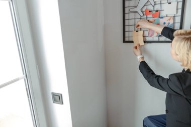 Bayan işyerindeki özel tahtaya notlar yerleştiriyor.