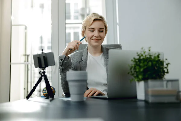 Усміхнена красива леді сидить і працює в її офісі — стокове фото