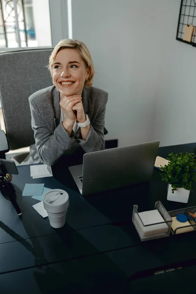 Mulher bonita feliz sentado e olhando para cima no escritório — Fotografia de Stock