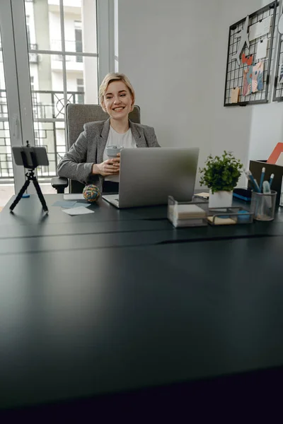 Feliz bonita fêmea gostando de café no escritório — Fotografia de Stock