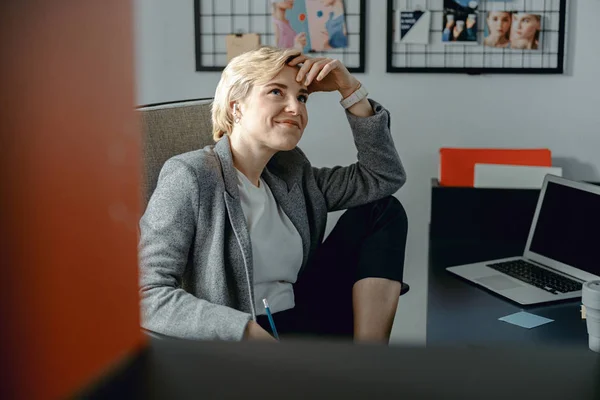 Smiling young lady listening to music on headphones in office — 스톡 사진