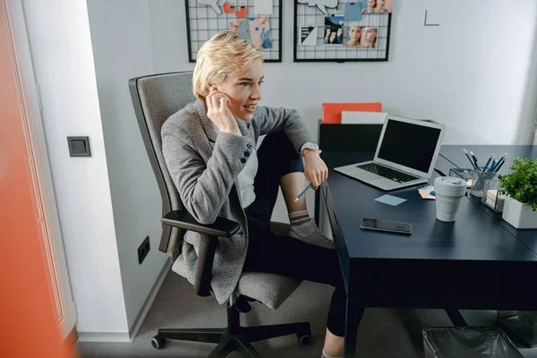 Happy young woman using headphones at workplace — 스톡 사진