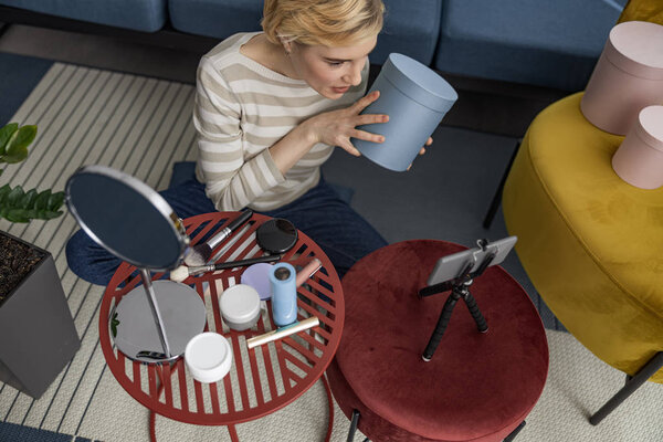 Красивая молодая женщина держит коробку и показывает на камеру
