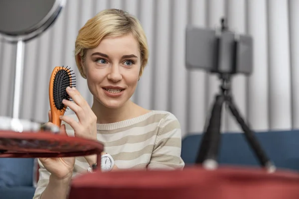 Happy young woman using comb for her vlog — Stock Photo, Image