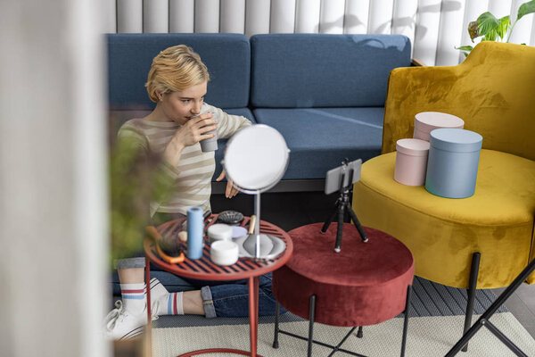 Счастливая красивая женщина сидит рядом с диваном с кофе
