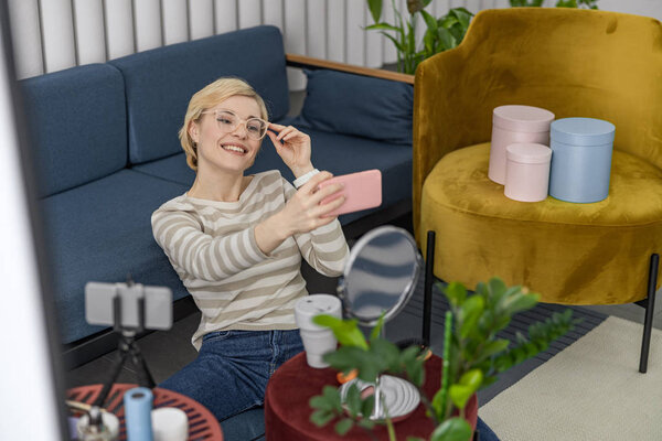 Счастливая молодая женщина в очках с помощью мобильного телефона
