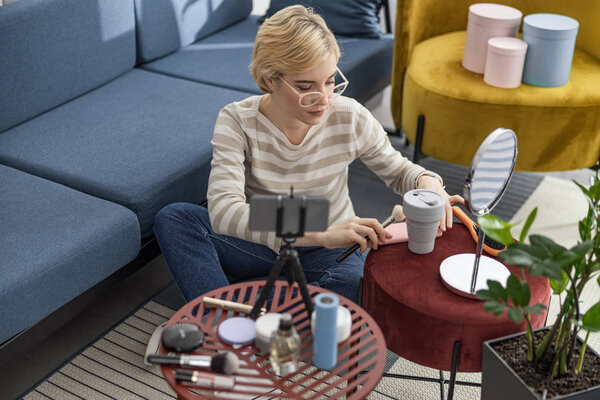 Красивая молодая женщина сидит на полу и использует мобильный телефон
