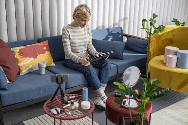 Улыбающаяся красивая женщина сидит на диване и работает
