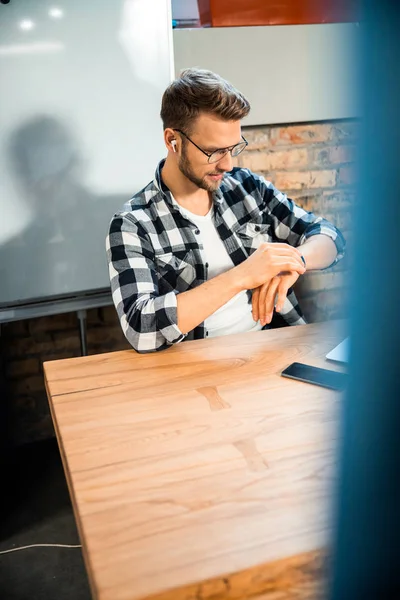 Jeune homme regardant la montre intelligente dans le bureau — Photo