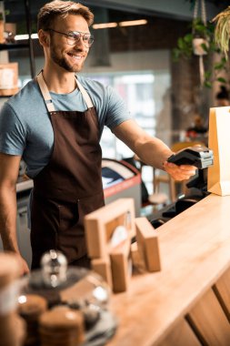Kredi kartı okuyucu makinesi tutan mutlu barista.