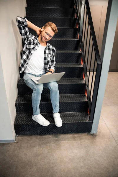 Jovem feliz trabalhando em escadas dentro de casa — Fotografia de Stock