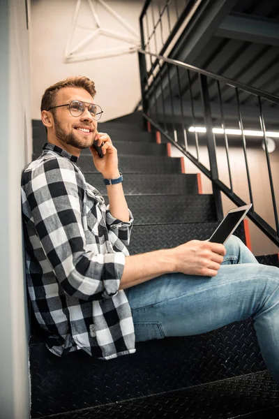 Smiling young guy using mobile phone indoors — Stock Photo, Image