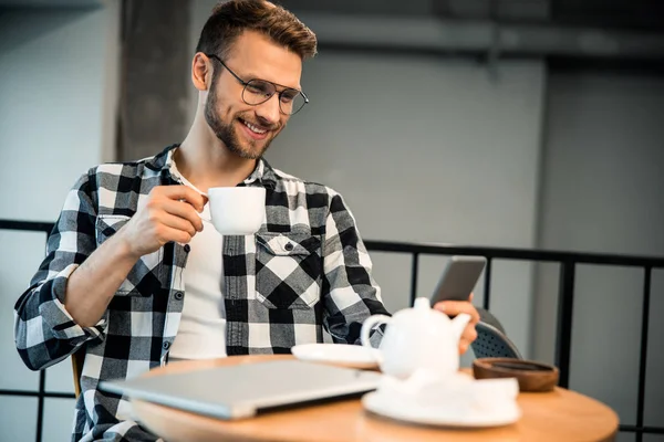 Heureux blogueur masculin en utilisant smartphone dans le café — Photo