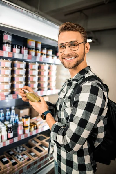Χαμογελώντας νεαρός κρατώντας ένα μπουκάλι σε ένα σούπερ μάρκετ — Φωτογραφία Αρχείου