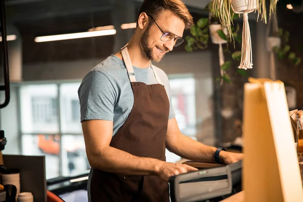 Joven feliz trabajando en una cafetería — Foto de Stock