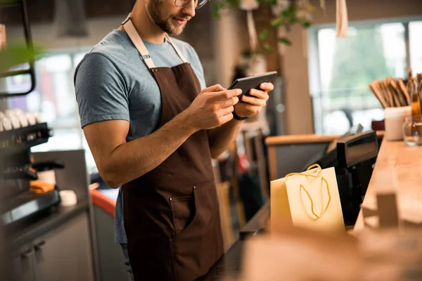 Barista sonriente sosteniendo una tableta en una cafetería — Foto de Stock