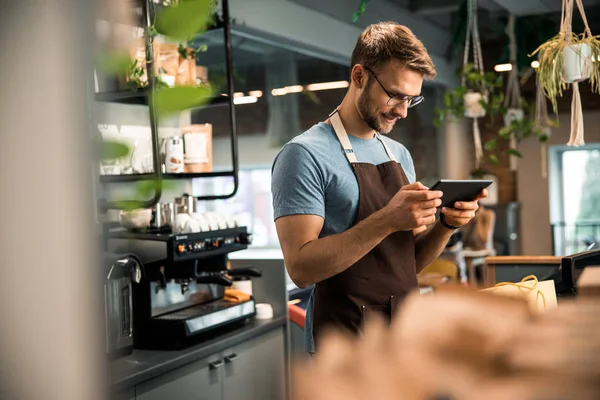 Heureux jeune barista regardant écran de tablette dans le café — Photo