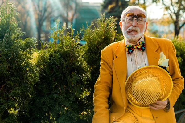 Ηλικιωμένος άνδρας με αστείο κοστούμι στέκεται και παιχνιδιάρικα δείχνει τη γλώσσα — Φωτογραφία Αρχείου
