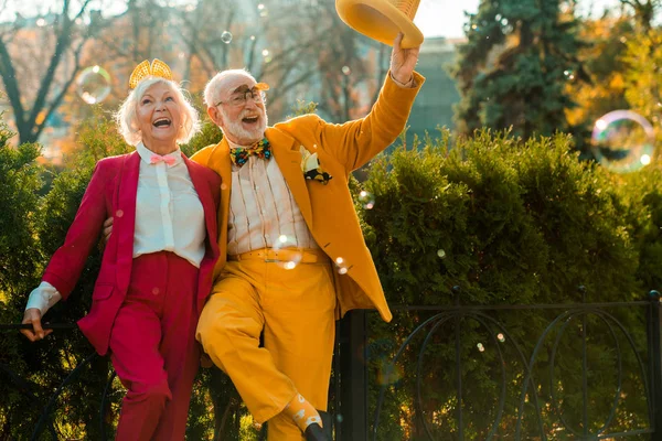 Legrační starší žena se směje v parku vedle svého manžela — Stock fotografie